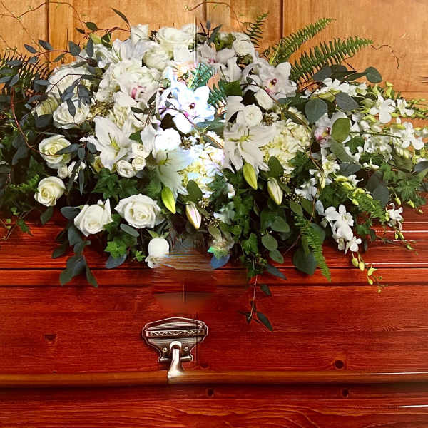White floral spray on a polished wooden casket