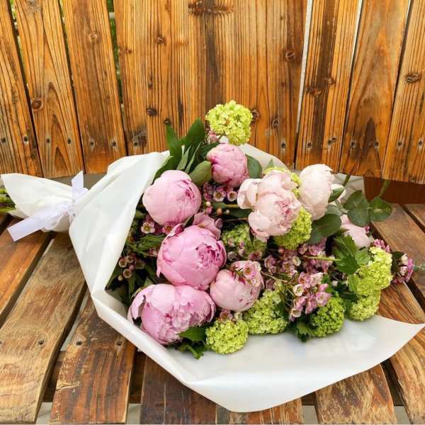 Pink peonies and green blooms wrapped in white paper