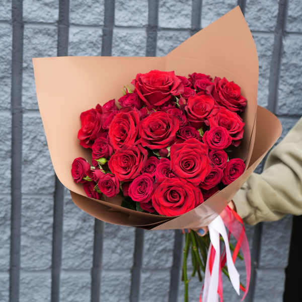 Bouquet of red roses wrapped in tan paper with red and white ribbons