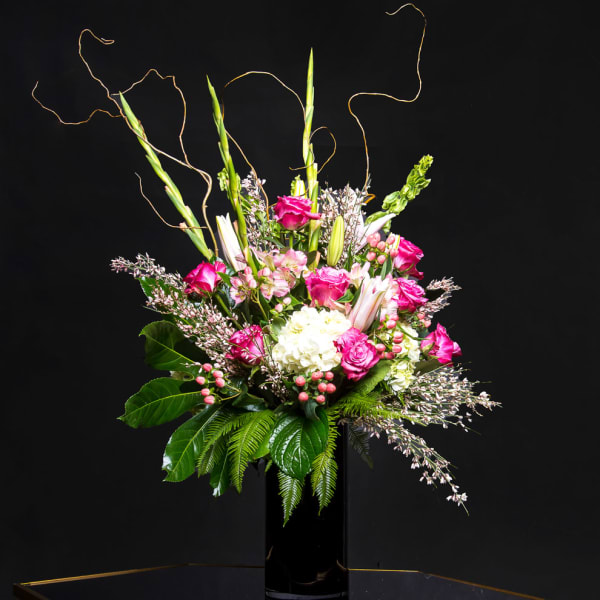 Pink and white floral arrangement in a black vase