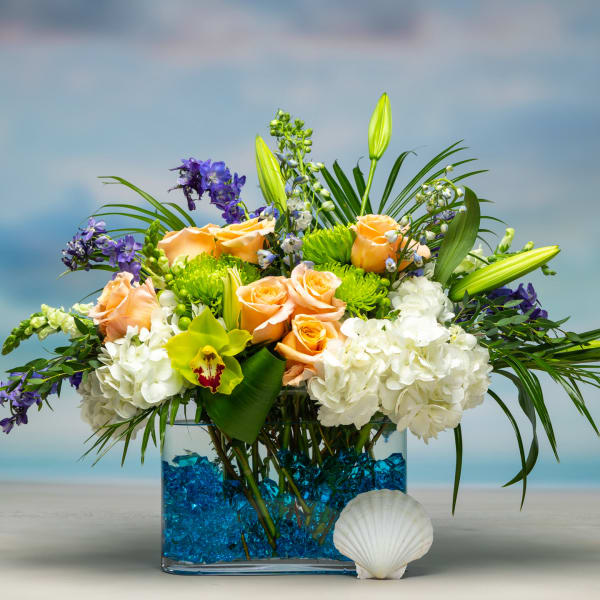 Arrangement of peach roses, white hydrangeas, and purple flowers in a blue vase