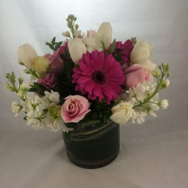 Pink and white mixed flower arrangement in a dark vase