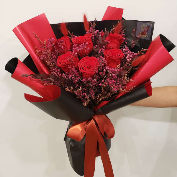 Bouquet of red roses wrapped in black and red paper with a ribbon