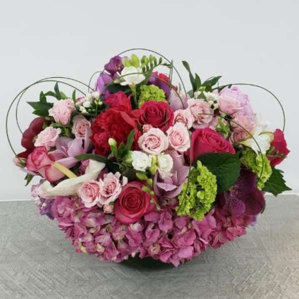 Large pink and red mixed flower arrangement with roses and hydrangeas