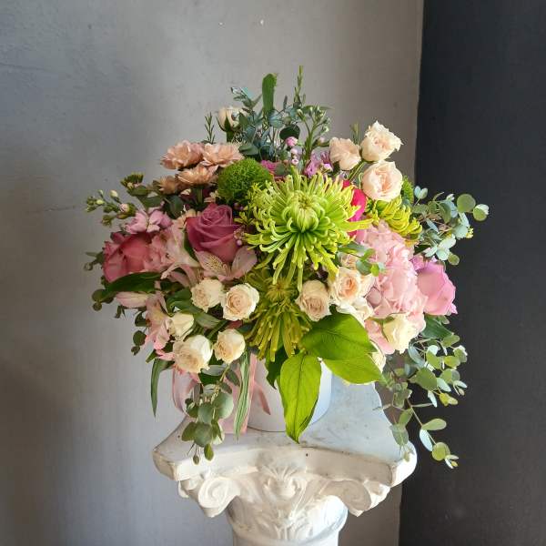 Mixed bouquet with pink and cream flowers in a white vase