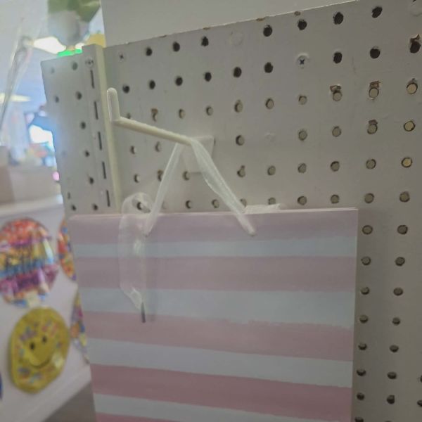 Pink and white striped gift bag hanging on a pegboard display