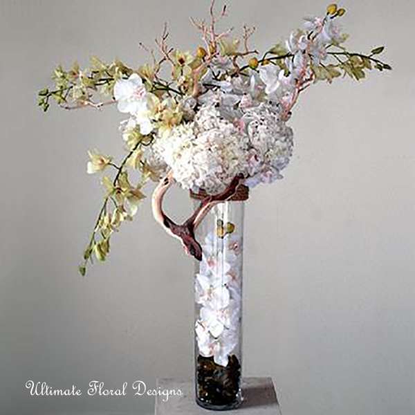 Tall white floral arrangement in a clear glass vase with arching branches