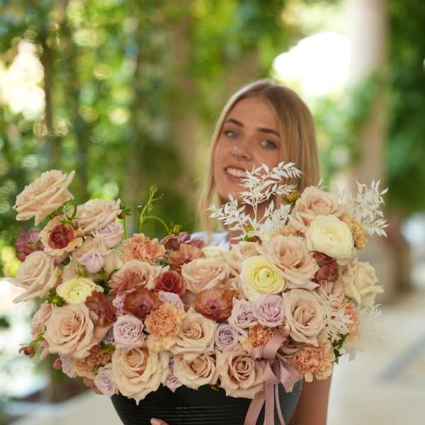 Woman holding a large pastel bouquet in a black container