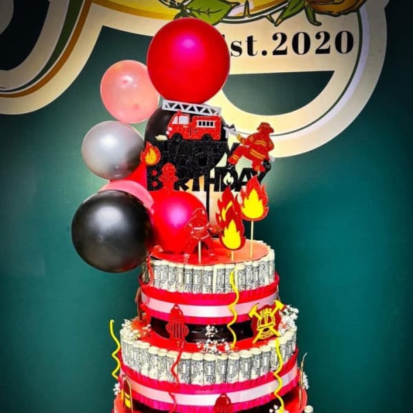 Tiered birthday cake with balloons and fireman decorations