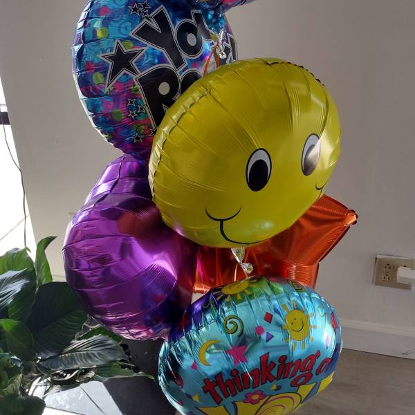 Cluster of colorful birthday balloons with smiley faces and text