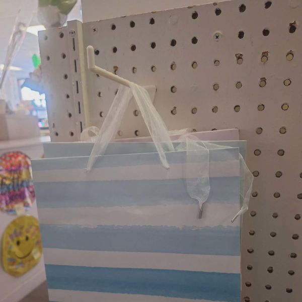 Striped blue-and-white gift bag hanging on a pegboard display
