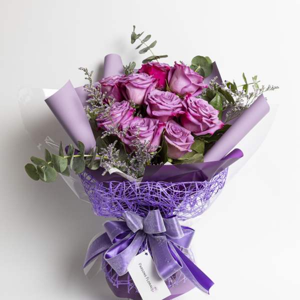 Bouquet of purple roses wrapped in lavender paper with a ribbon