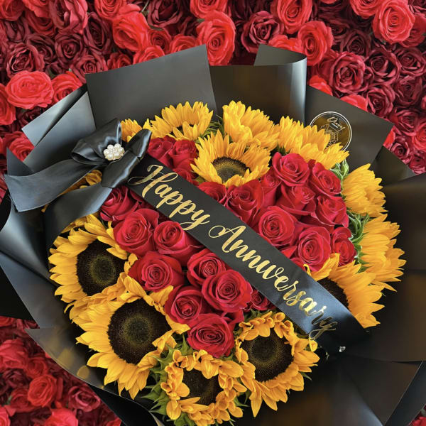 Bouquet of red roses and yellow sunflowers wrapped in black paper