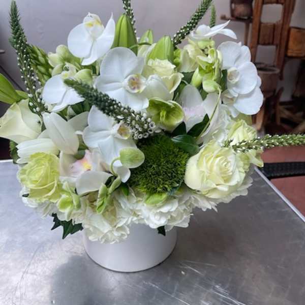White and pale green floral arrangement in a white vase