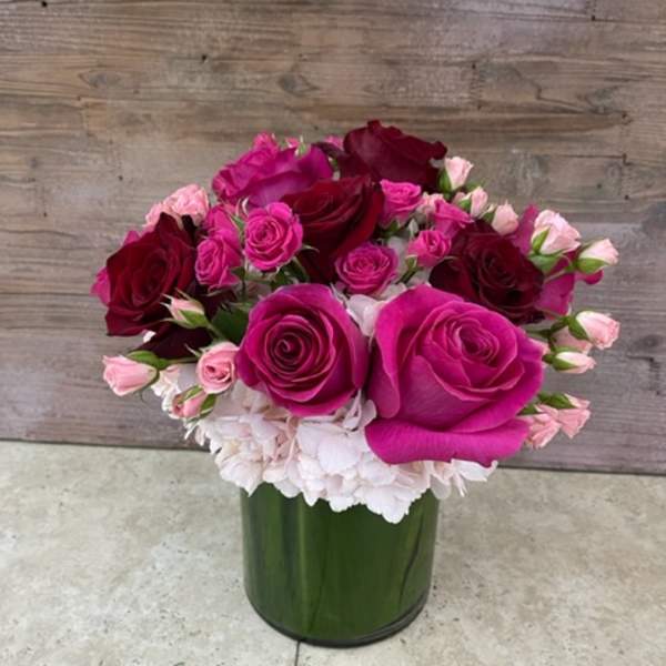 Pink and burgundy roses arranged in a green glass vase