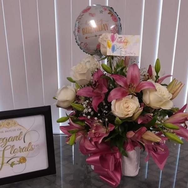 Pink lilies and white roses in a vase with a birthday balloon