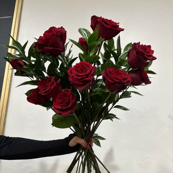 Handheld bouquet of red roses with greenery