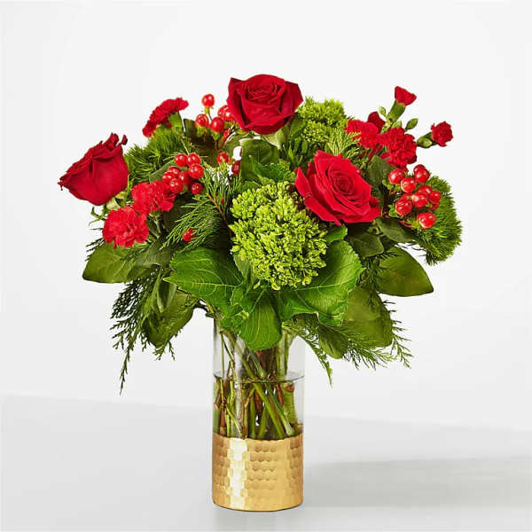 Red roses and carnations arranged in a glass vase with green accents