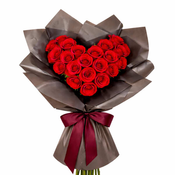 Heart-shaped bouquet of red roses wrapped in dark paper with a burgundy ribbon