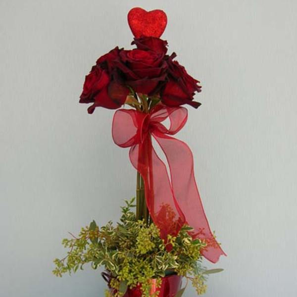 Tall red rose arrangement in a red vase with a sheer ribbon