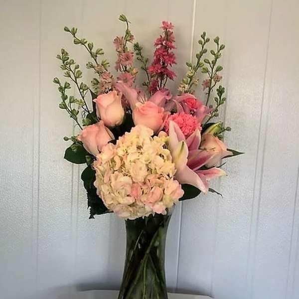 Pink and peach floral arrangement in a tall glass vase