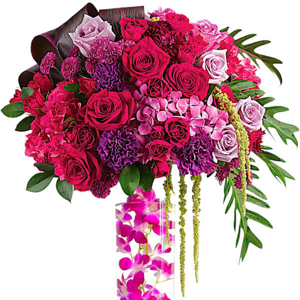 Pink and purple rose arrangement in a tall clear vase with orchids