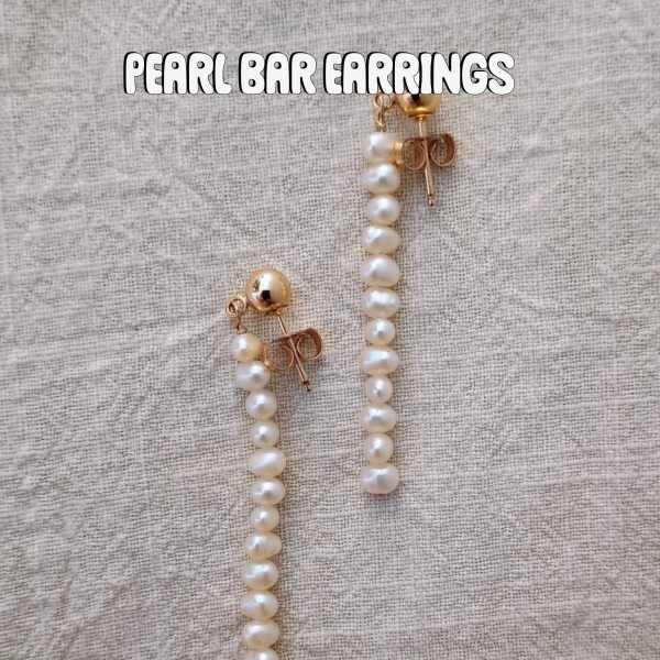 Pair of pearl drop earrings on a textured fabric background