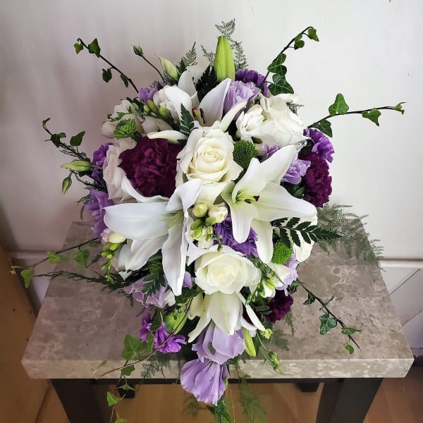 White lilies and roses with purple flowers in a low arrangement