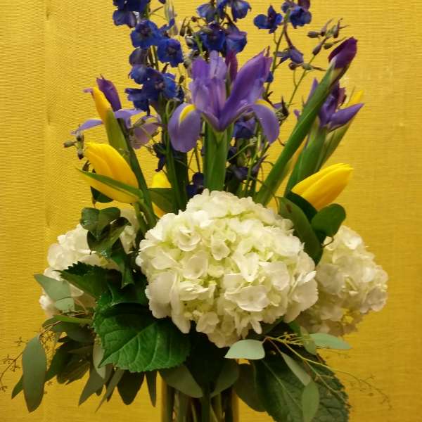 Bouquet of blue and purple flowers with white hydrangeas in a glass vase
