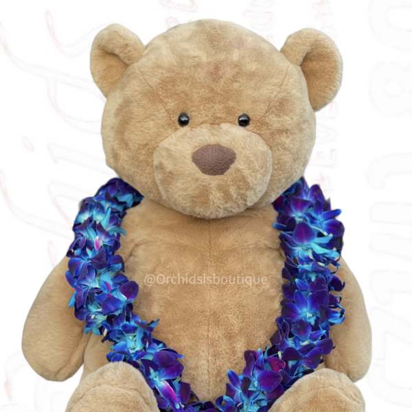 Tan teddy bear wearing a blue and purple flower lei