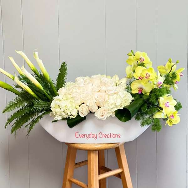 White floral arrangement with calla lilies, roses, hydrangea, and yellow orchids