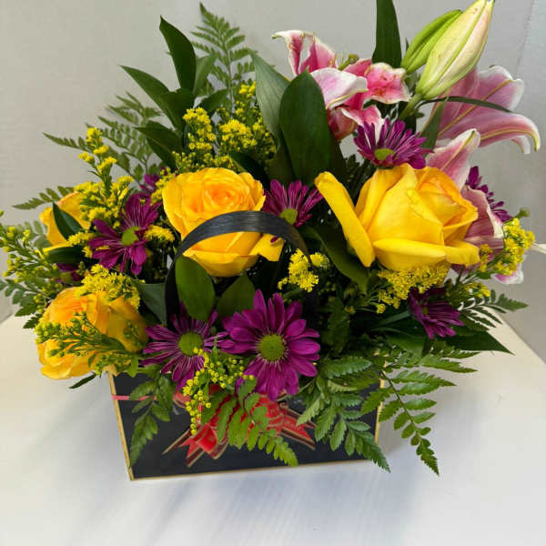 Bouquet of yellow roses, pink lilies, and purple daisies in a gift box