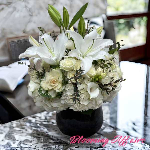 White lilies and roses arranged in a black vase
