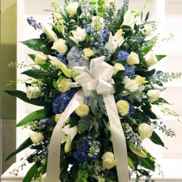 Tall white and blue floral standing spray with a ribbon bow