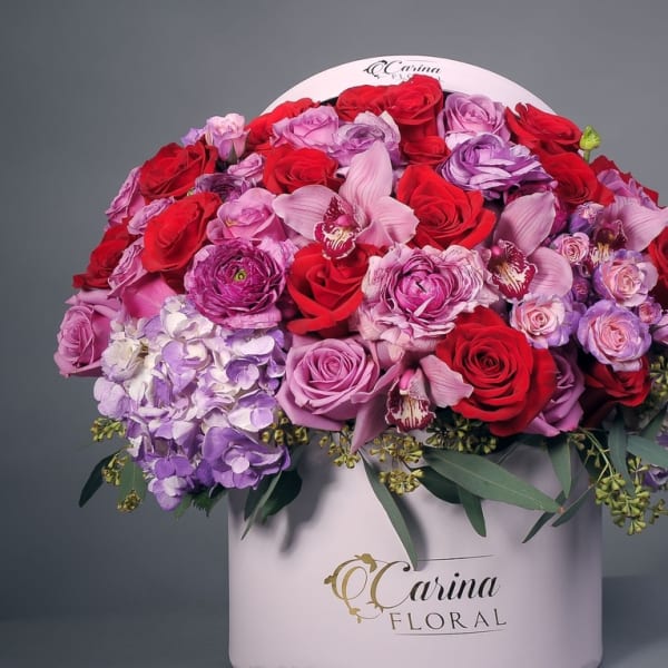 Large bouquet of red, pink, and purple flowers in a white box