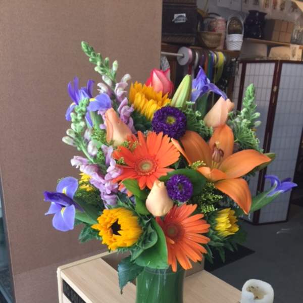 Colorful mixed bouquet in a glass vase with lilies and gerbera daisies