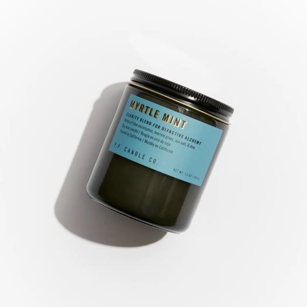 Dark glass candle jar with a blue label on a white background