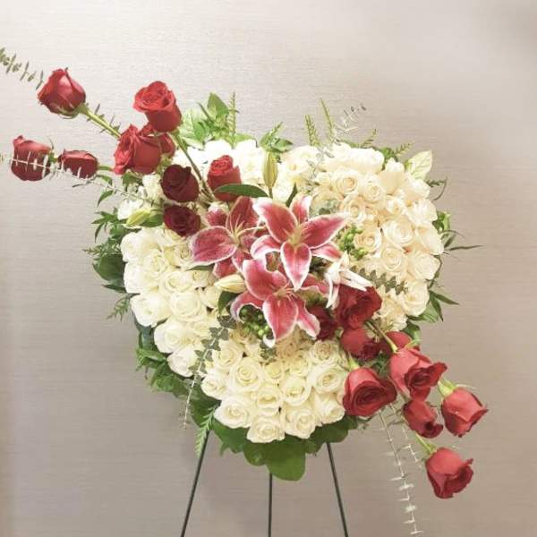 Heart-shaped rose arrangement with pink lilies on a stand