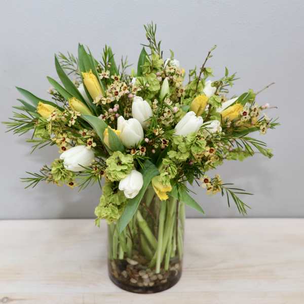 Bouquet of white tulips and yellow flowers in a glass vase
