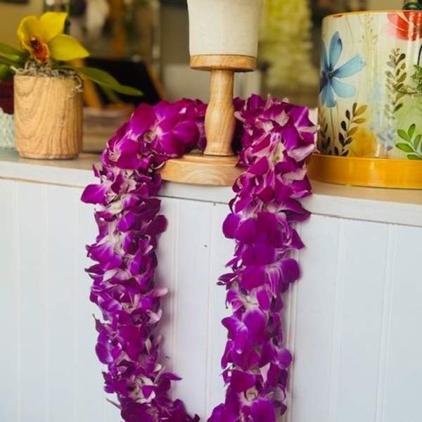 Purple orchid lei draped over a wooden stand