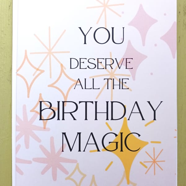 Birthday card with text 'You deserve all the birthday magic' and pastel starburst shapes on a white background