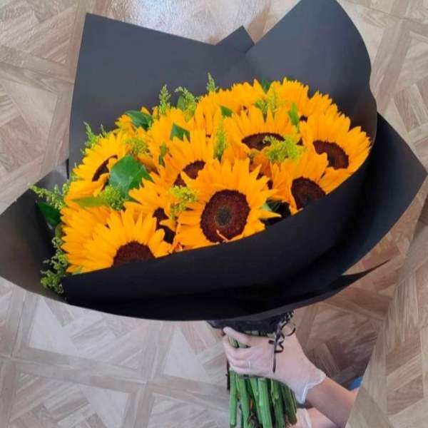 Bouquet of bright yellow sunflowers wrapped in black paper