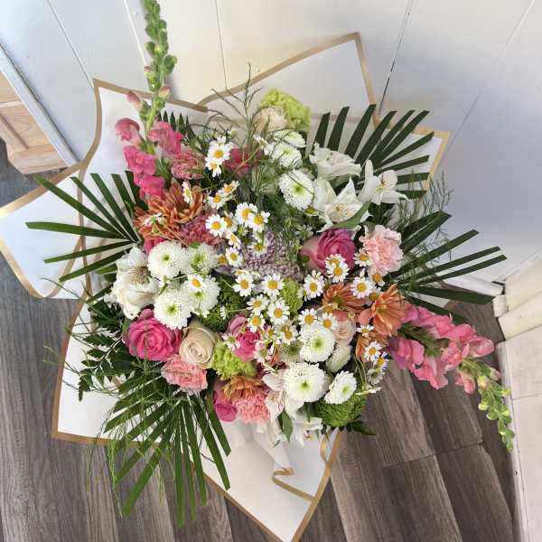 Mixed bouquet of pink, white, and green flowers wrapped in white paper