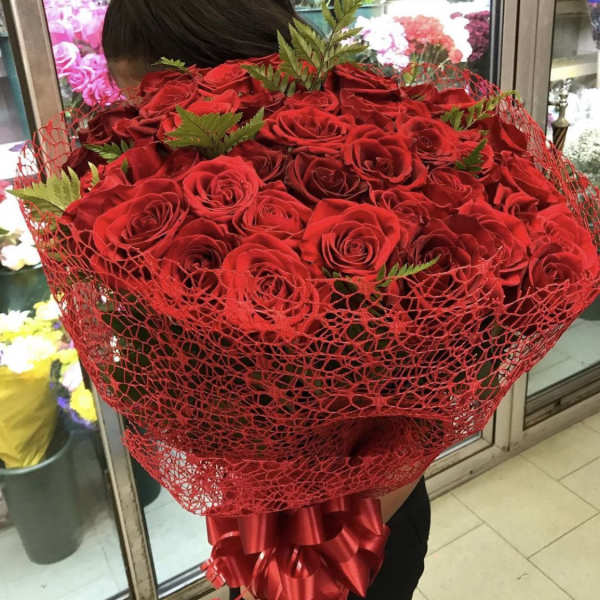 Large bouquet of red roses wrapped in red mesh with a satin ribbon