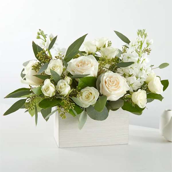White roses and white blooms arranged in a white rectangular box
