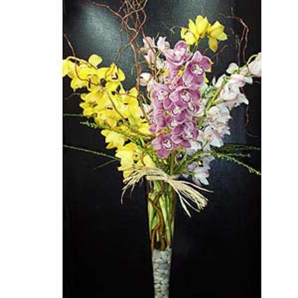 Tall bouquet of yellow, pink, and white orchids in a glass vase