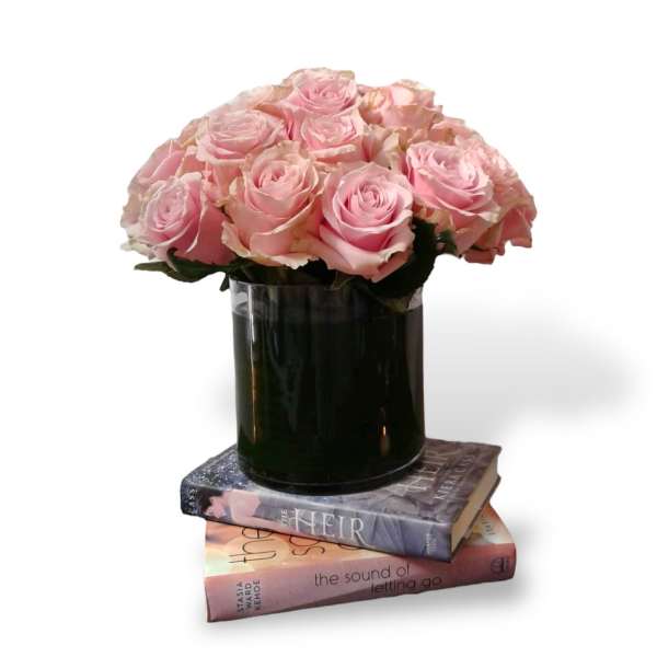 Pink roses in a dark glass vase stacked on two books