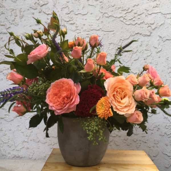 Peach and pink roses arranged in a gray vase