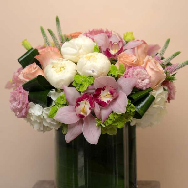 Pink and white floral arrangement in a tall glass vase