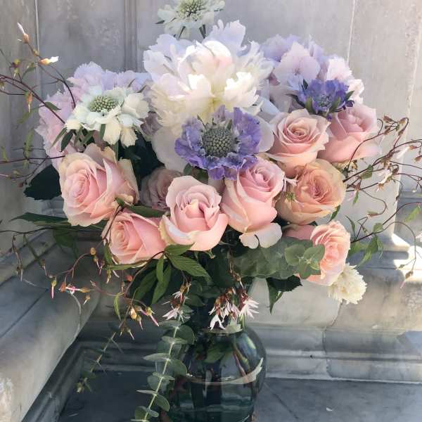 Pink roses and pastel blooms arranged in a glass vase